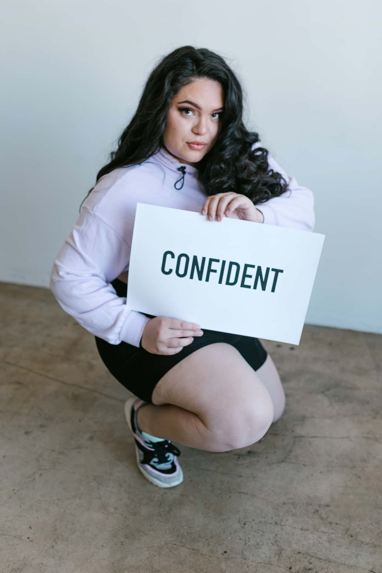 Curvy Woman Holding Confident Sign Wallpaper