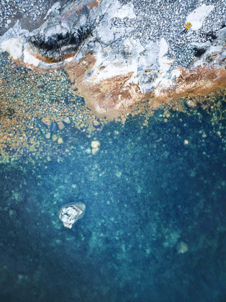 A Blue Water With A Rock In It Wallpaper