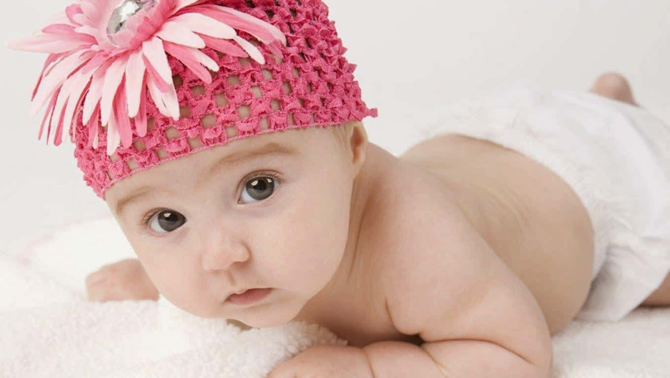 A Baby Wearing A Pink Flower Hat