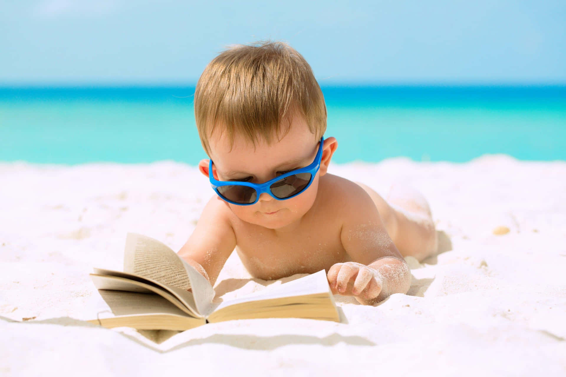 Einbaby Trägt Eine Sonnenbrille Und Liest Ein Buch Am Strand.