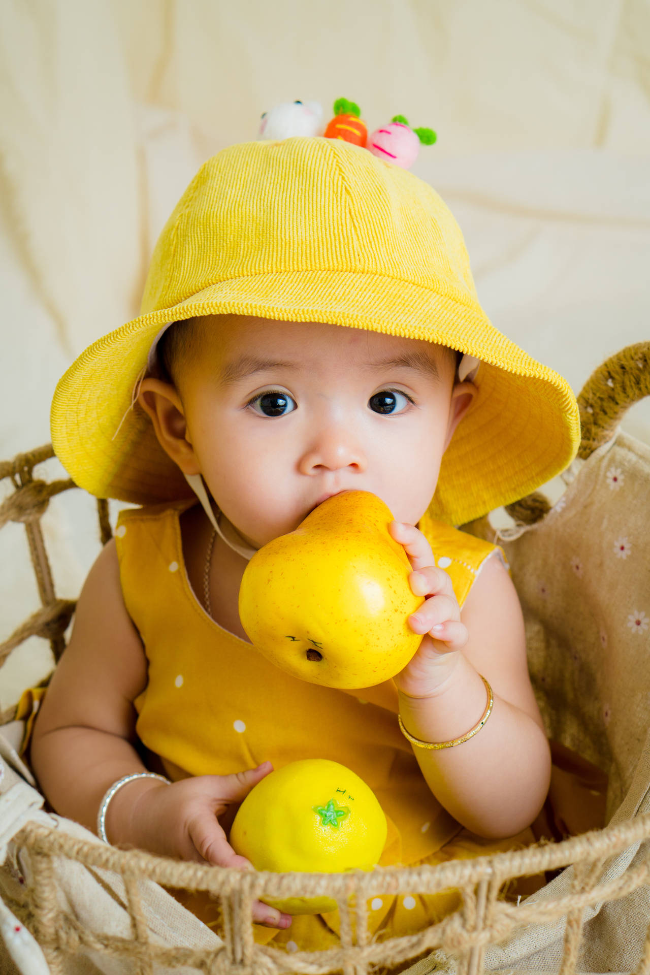 "Adorable Baby with Fruits in a Bucket Hat" Wallpaper