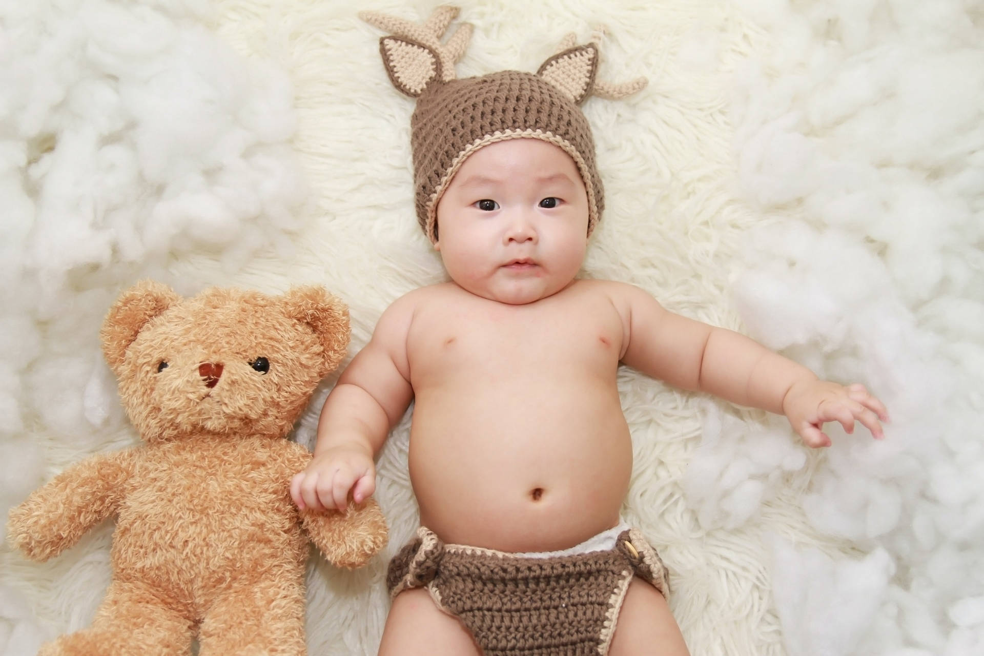 Sød baby med strikket hat og fyldt bamse Wallpaper