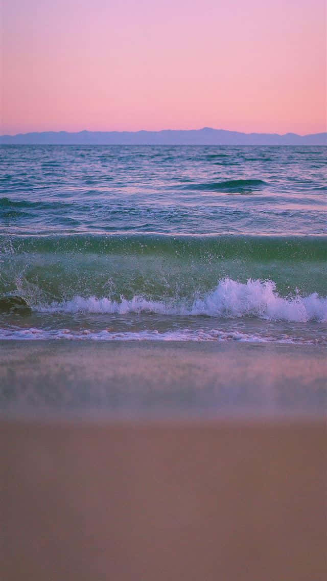 A Beach With Waves And A Sunset Wallpaper