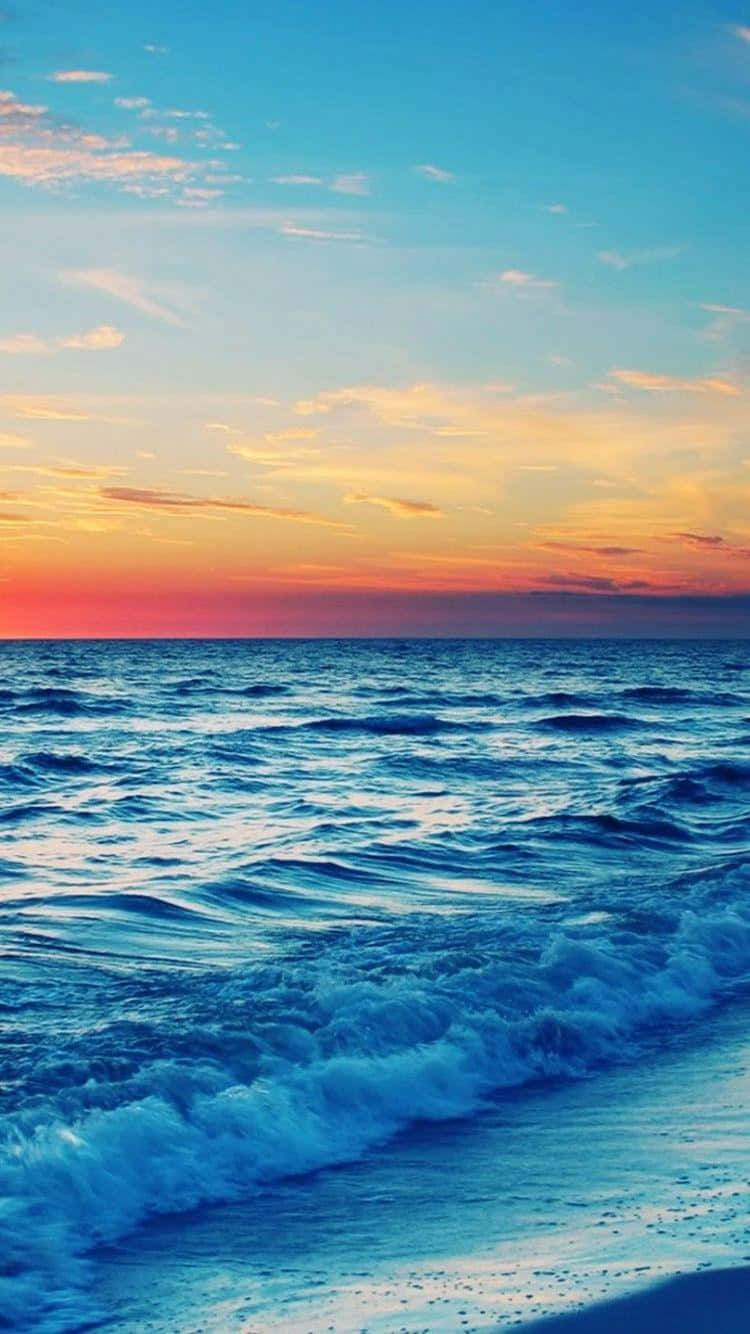 A Beach With Waves At Sunset Wallpaper