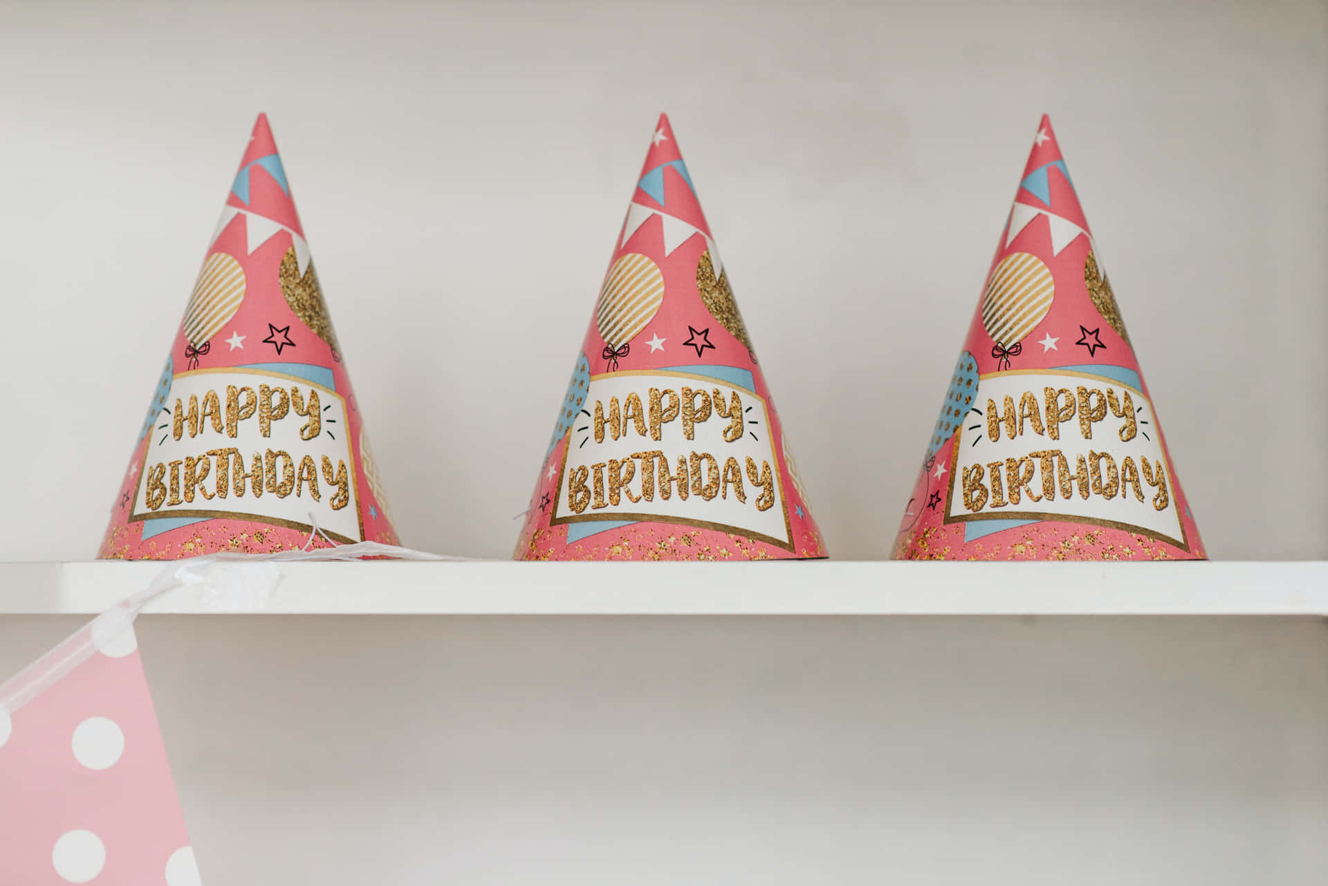 Three Pink And White Party Hats On A Shelf Wallpaper