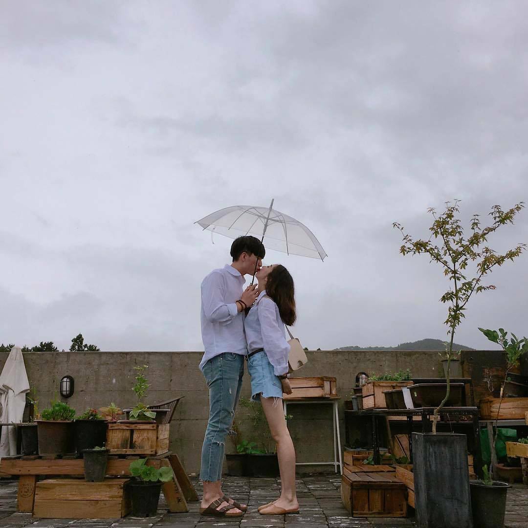 Cute Couple With Umbrella At A Rooftop Cafe