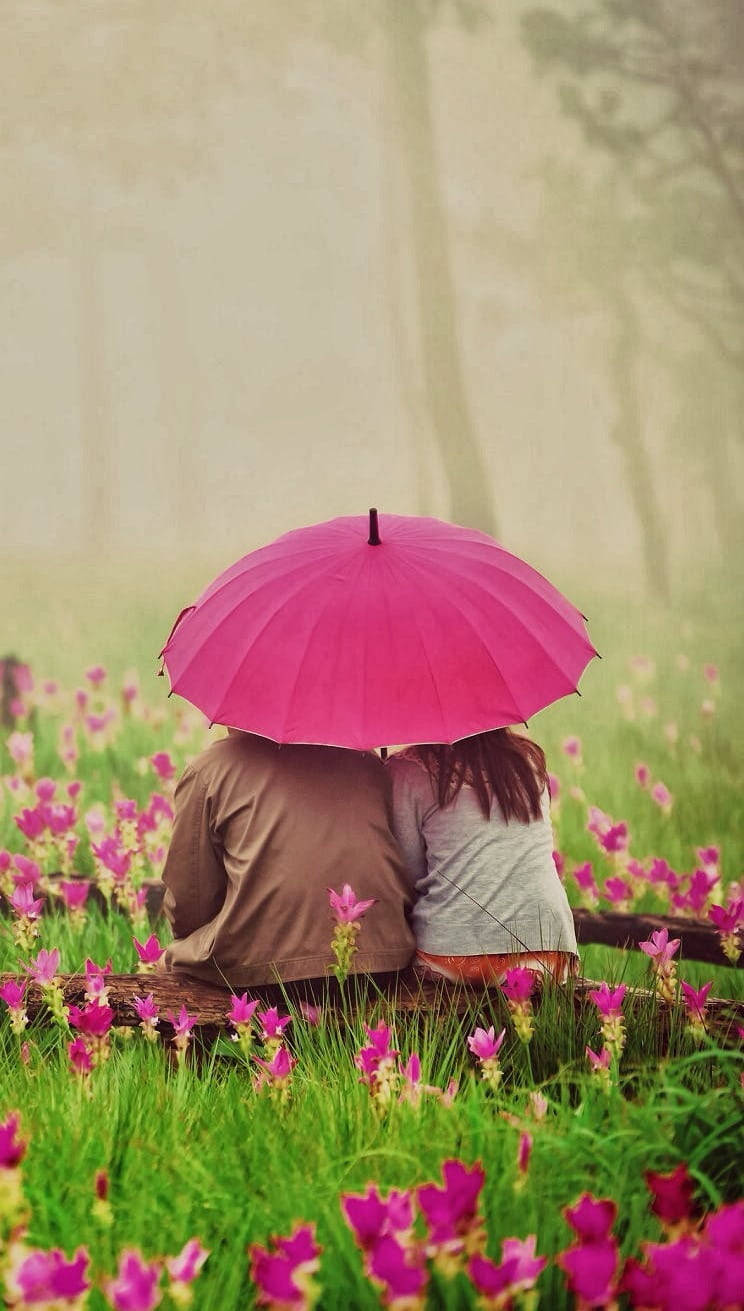 Sød par med paraply i blomsterhave Wallpaper