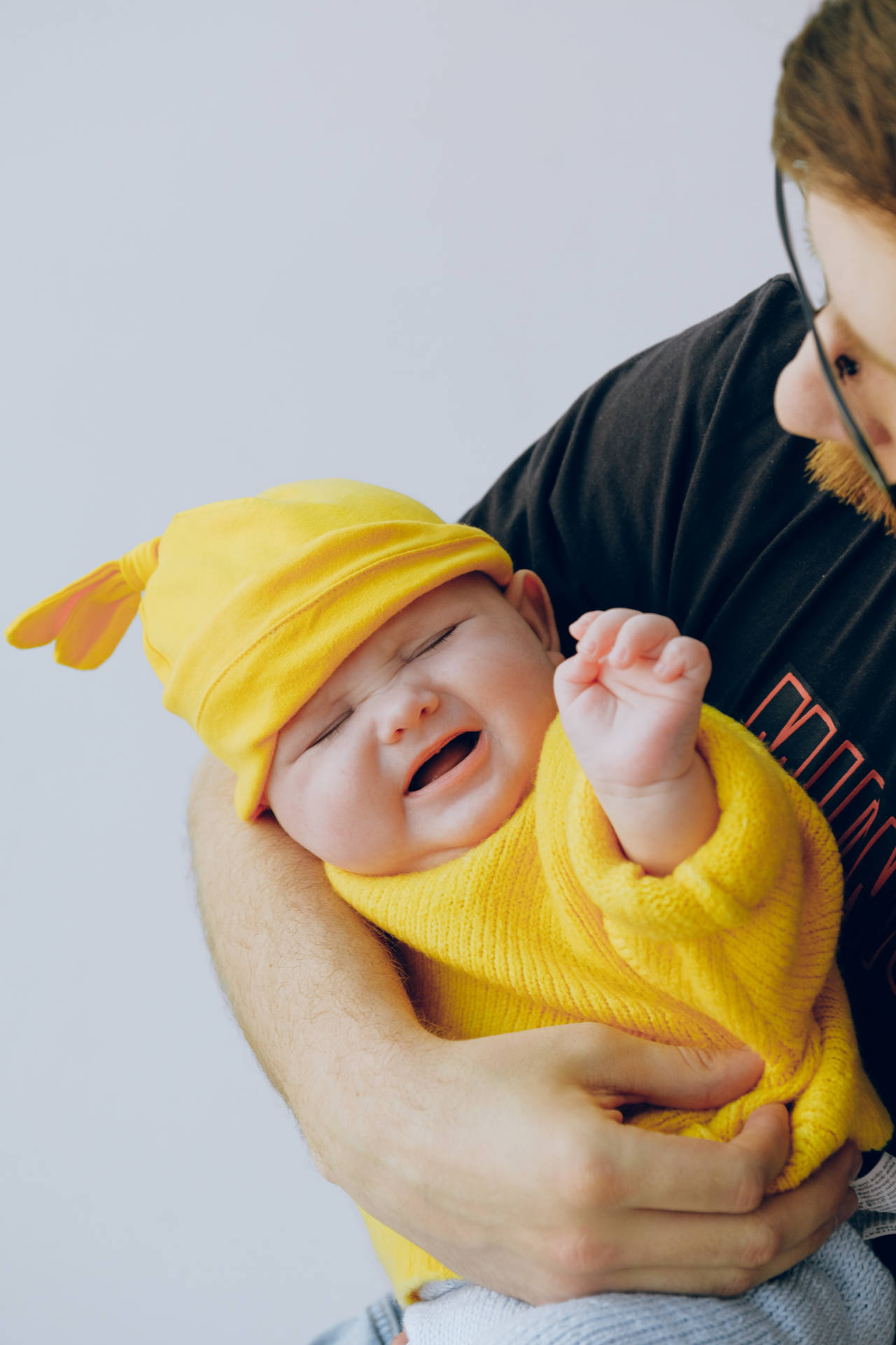 Sød grædende baby i gul dragt Wallpaper