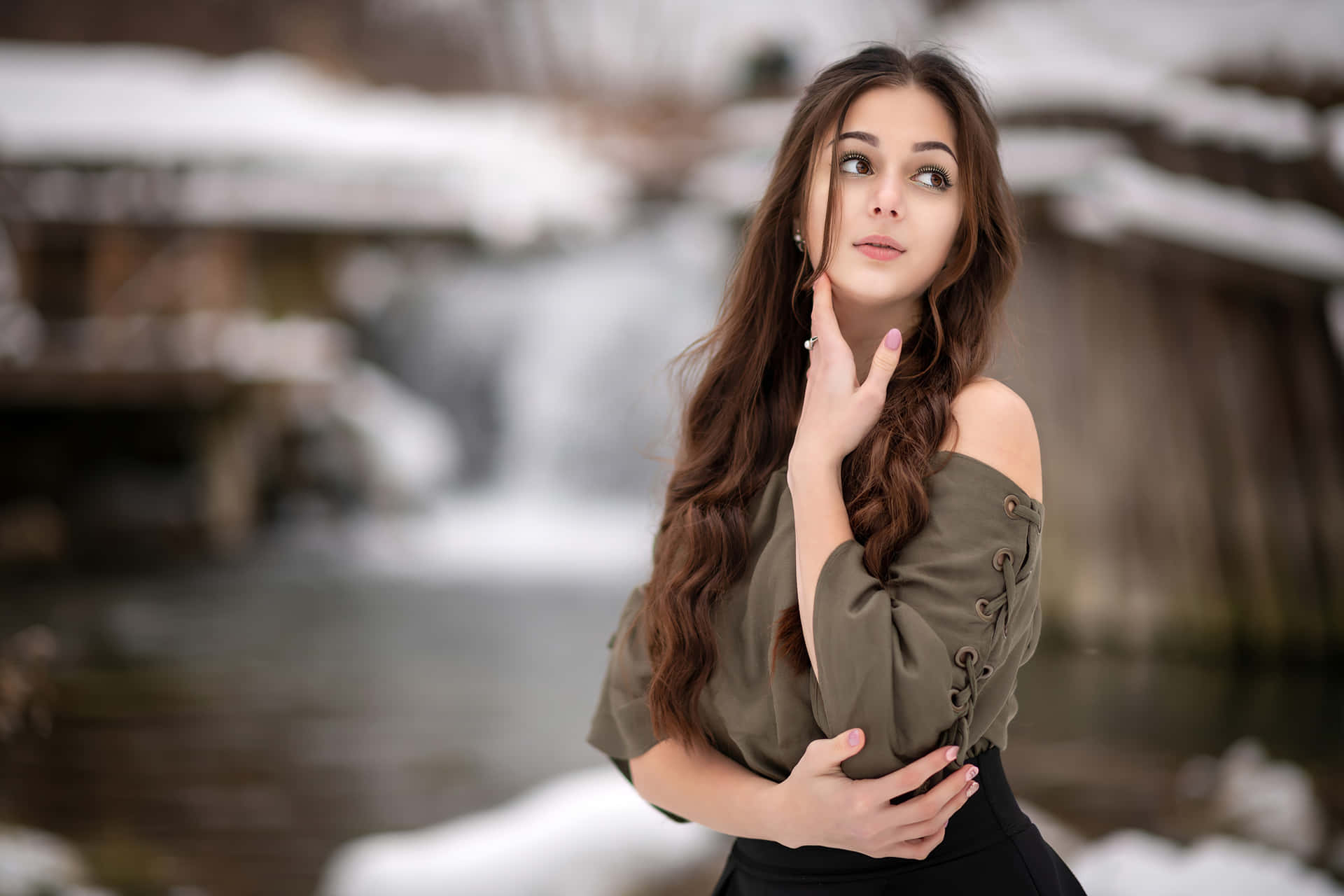 A Young Woman Standing In The Snow Near A Waterfall