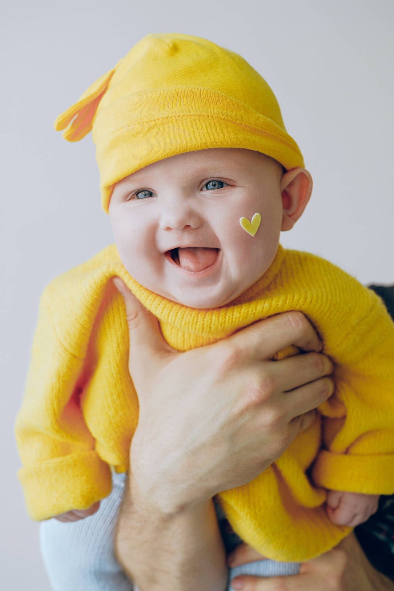 Sød latter baby i gul dragt Wallpaper