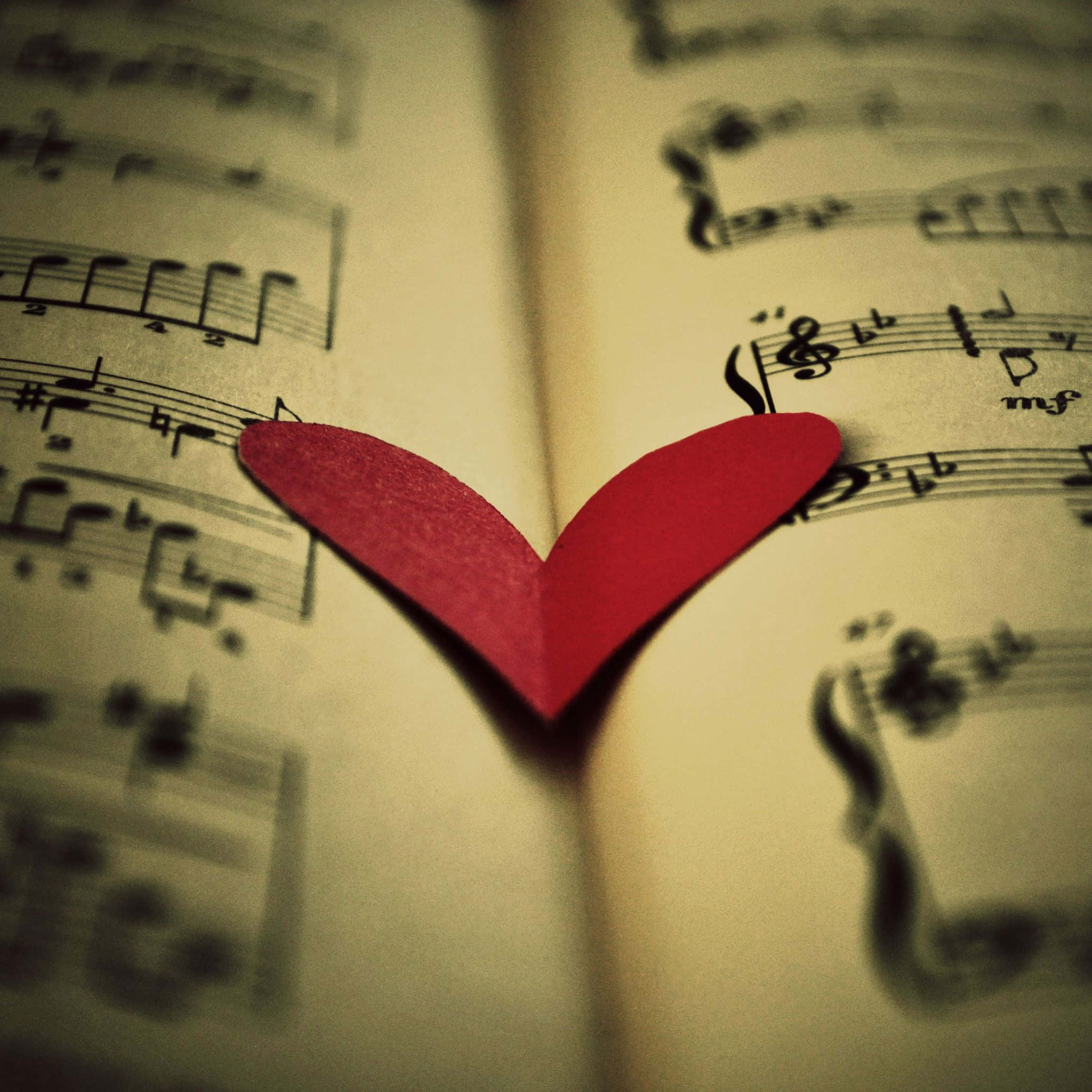 A Red Heart Is Placed On Top Of A Sheet Of Music