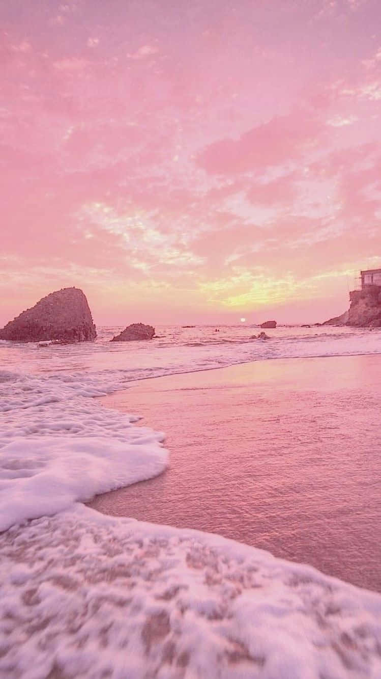A Pink Sunset With Waves On The Beach Wallpaper