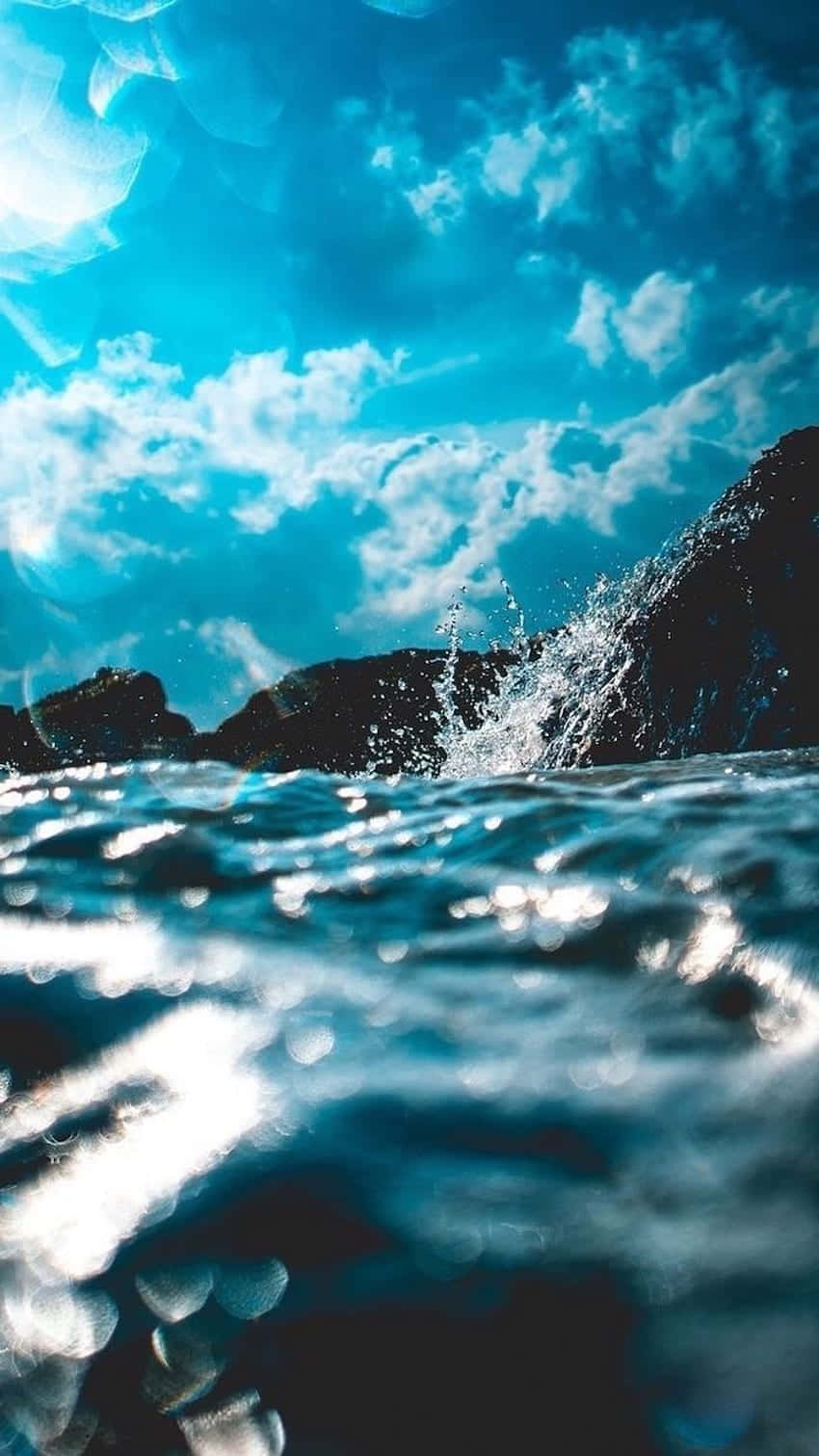 A Blue Sky With Clouds And Water Splashing Wallpaper