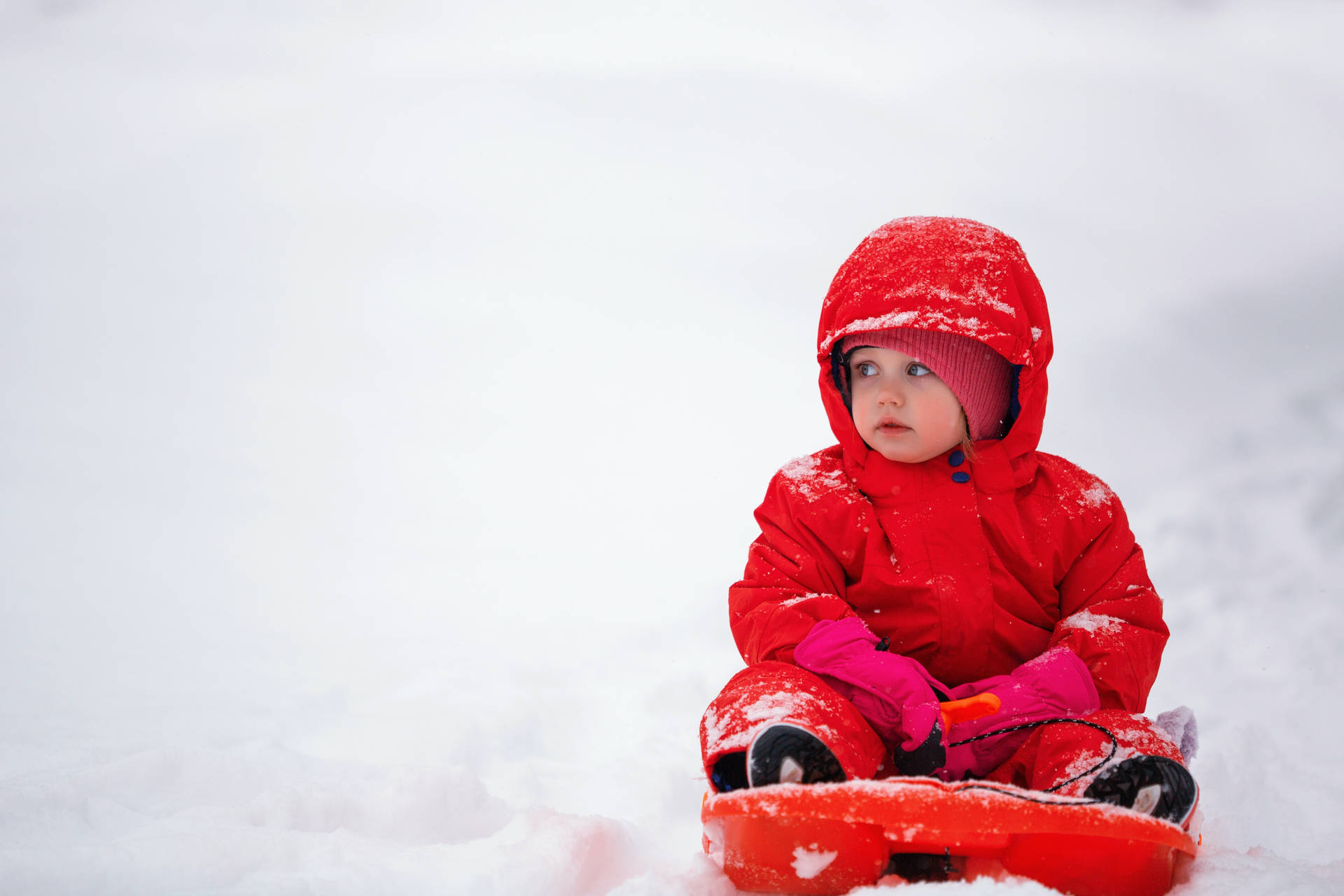 Cute Sledding Baby In Red Winter Clothes Wallpaper