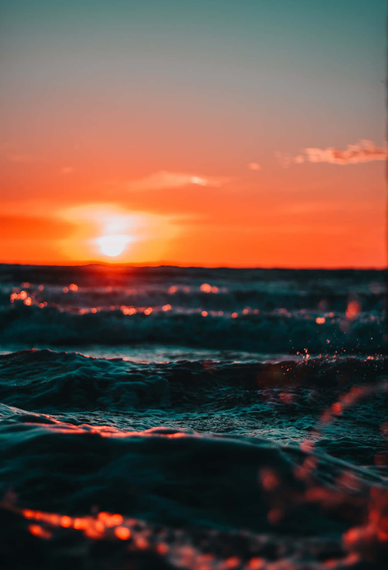 En solnedgang over havet med bølger, der styrtede ned. Wallpaper