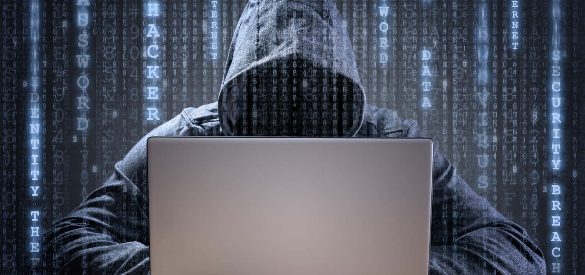 A Man In A Hoodie Is Sitting At His Laptop