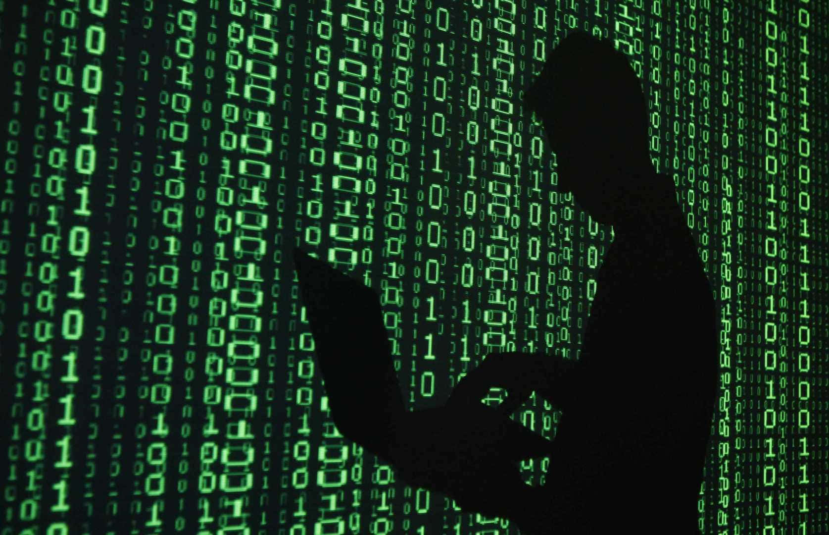A Silhouette Of A Man Using A Laptop In Front Of A Binary Code