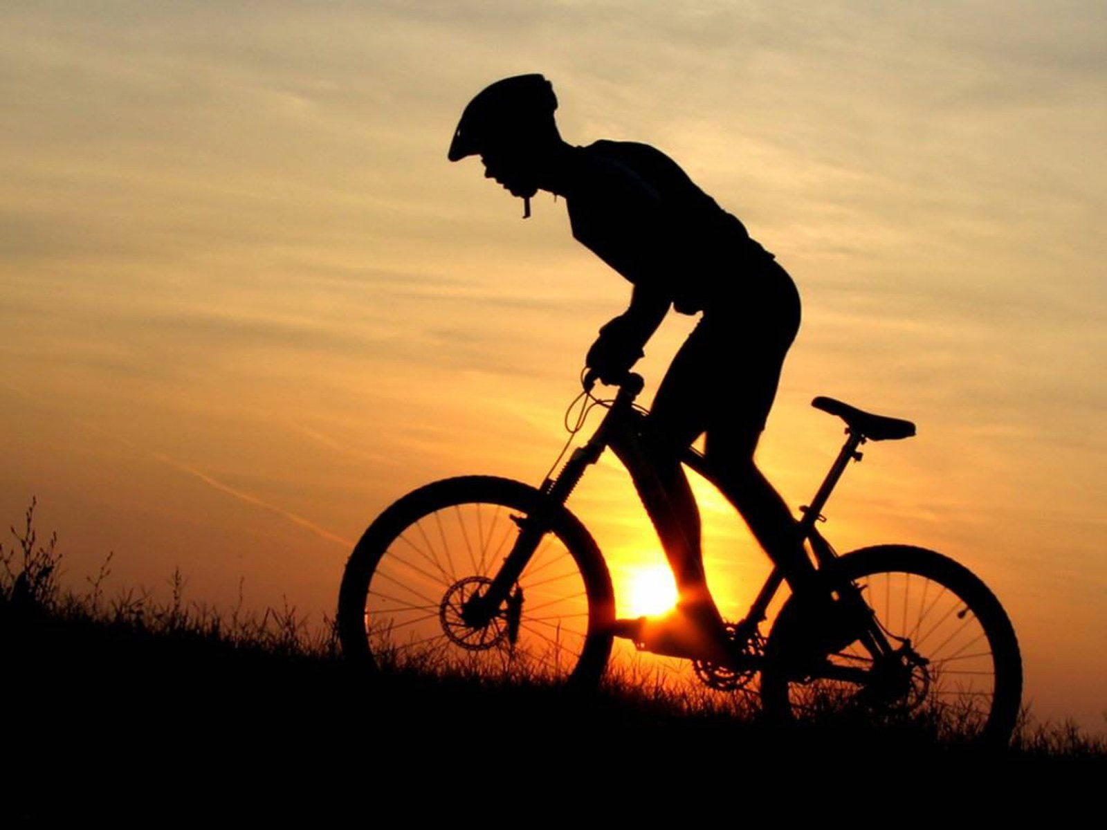 Cyclist On Bike Silhouette At Sunset Background