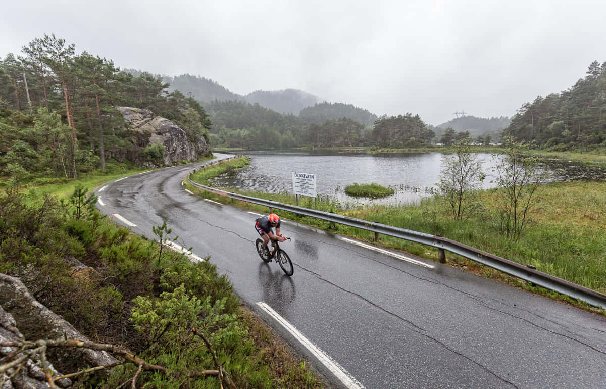 Cycliston Rainy Road Near Lake Haugesund Wallpaper