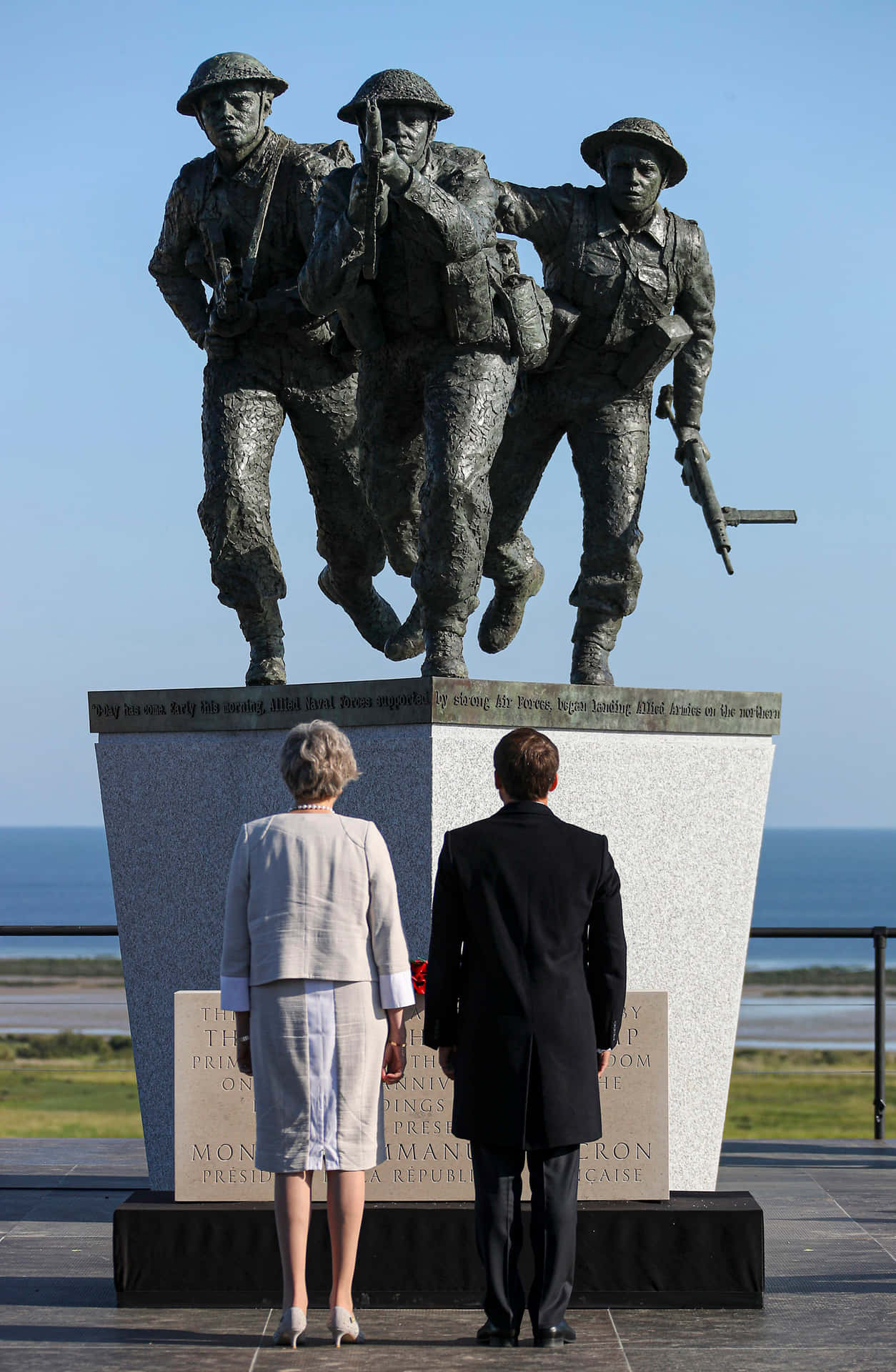A Man And Woman Standing In Front Of A Statue Of Soldiers