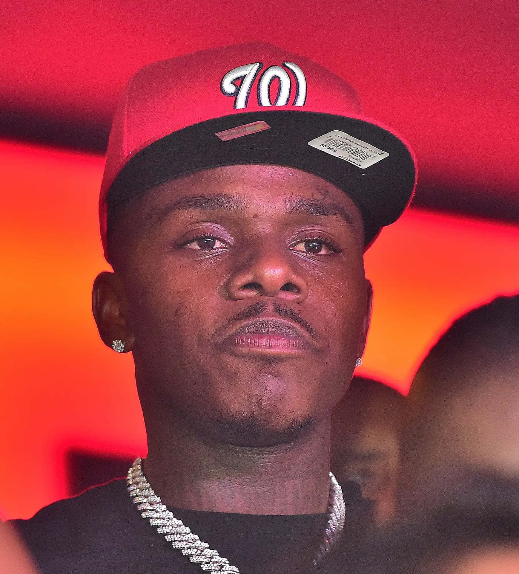 DaBaby performing live on stage, with an energetic and vibrant background