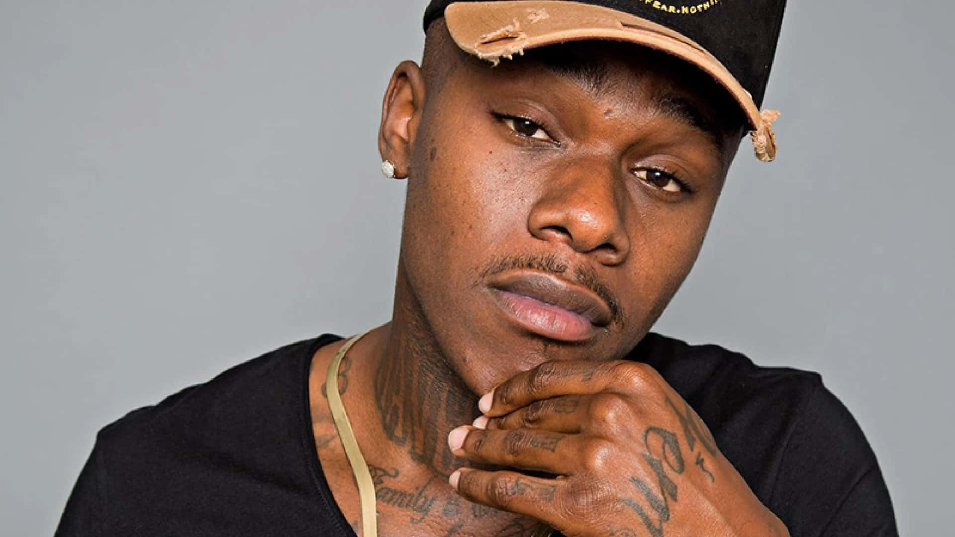 DaBaby Poses in a Stylish Outfit Against a Graffitied Wall