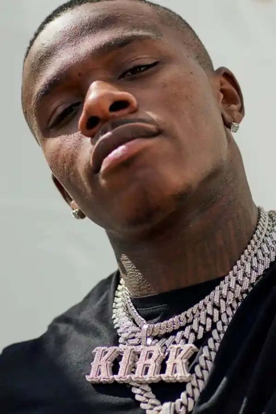 DaBaby in casual style, posing in front of a graffiti background