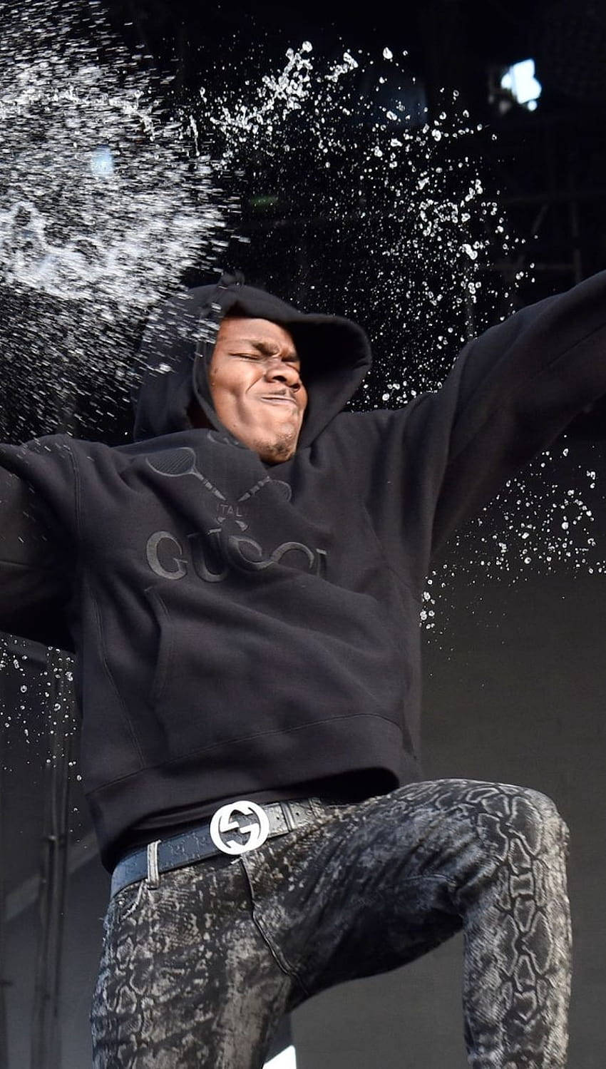 En mand i en sort hættetrøje kaster vand mod en scene. Wallpaper