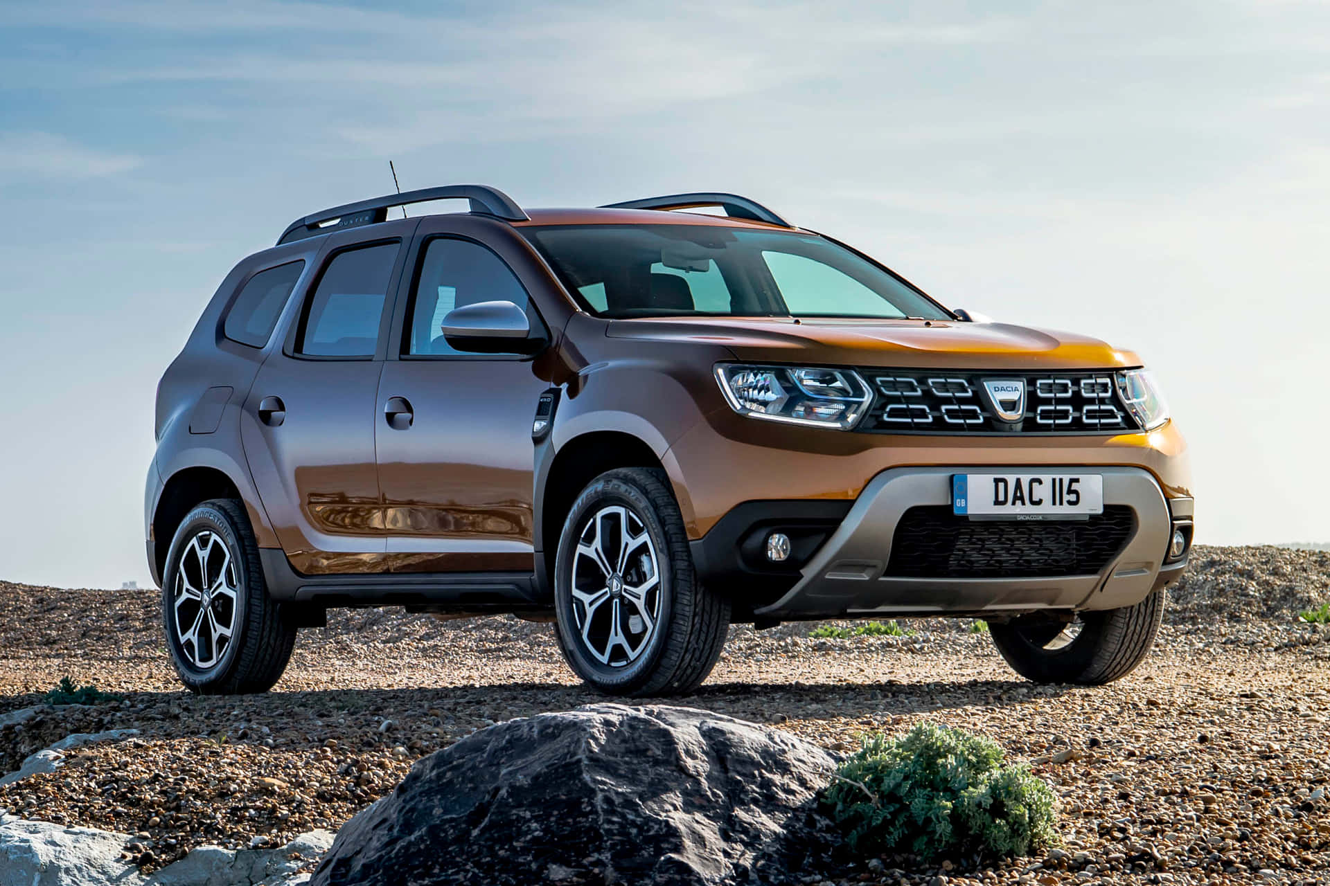 Dacia Duster driving on a scenic mountain road Wallpaper