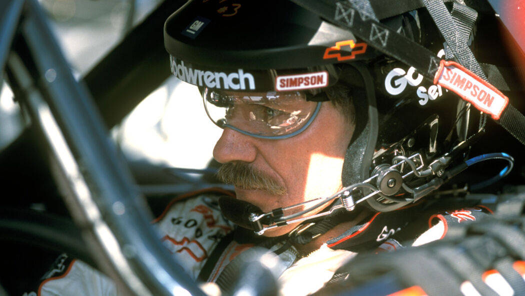 En mand i en racerbil iført hjelm og briller Wallpaper