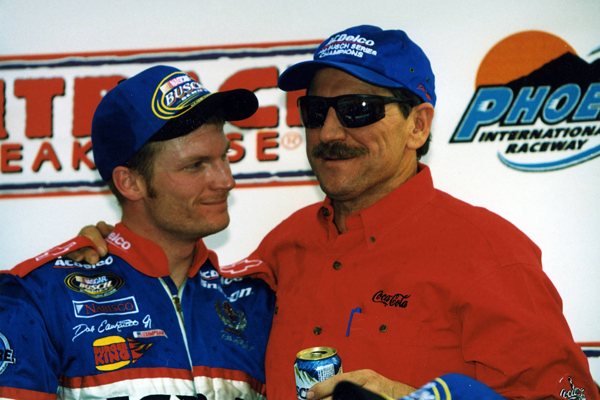 Two Men In Nascar Shirts And Hats Standing Next To Each Other Wallpaper