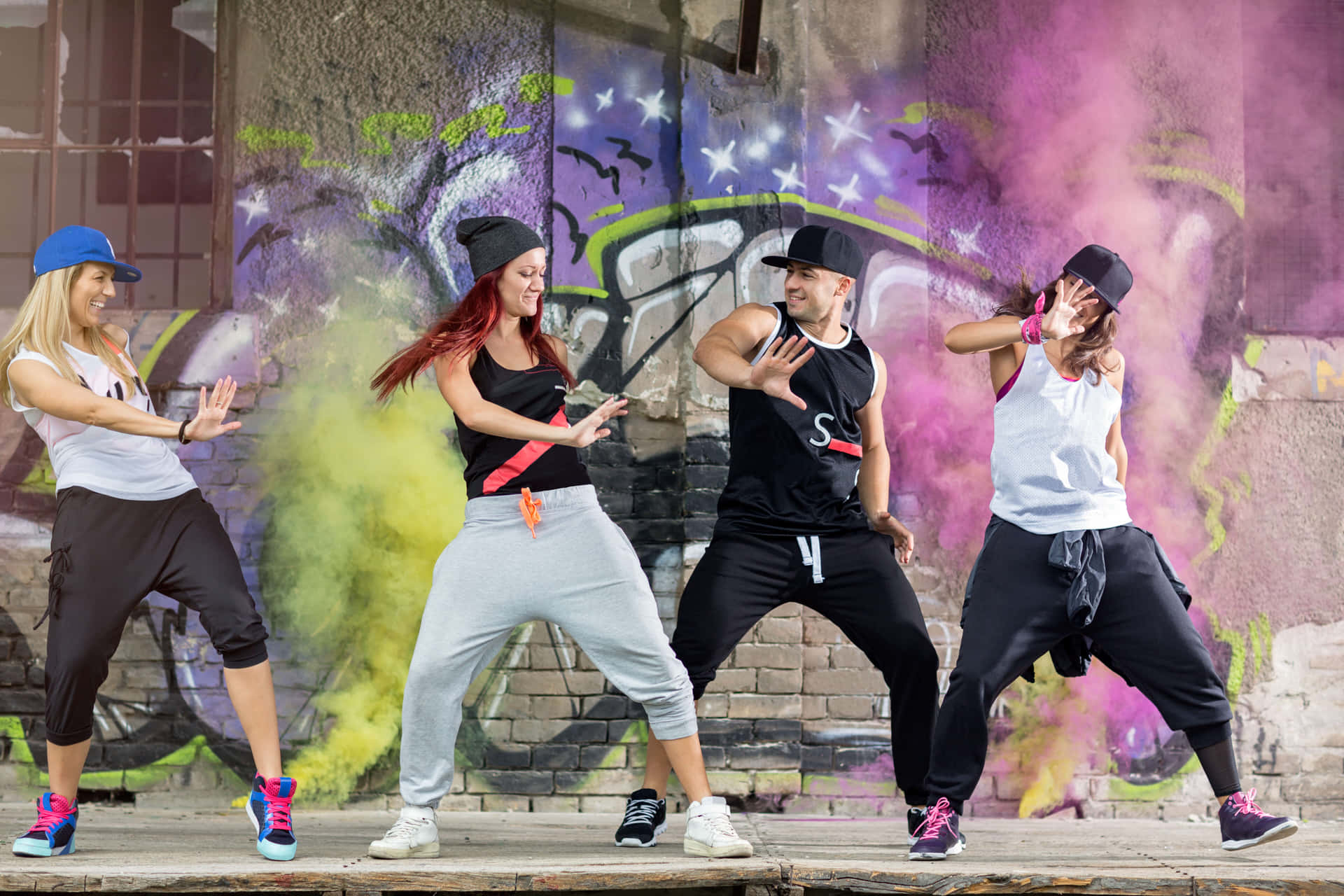 Viermenschen Tanzen Vor Einer Graffitiwand.
