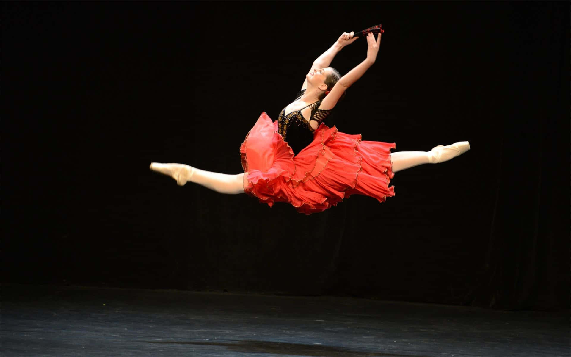 A Woman In A Red Dress Is Jumping On Stage