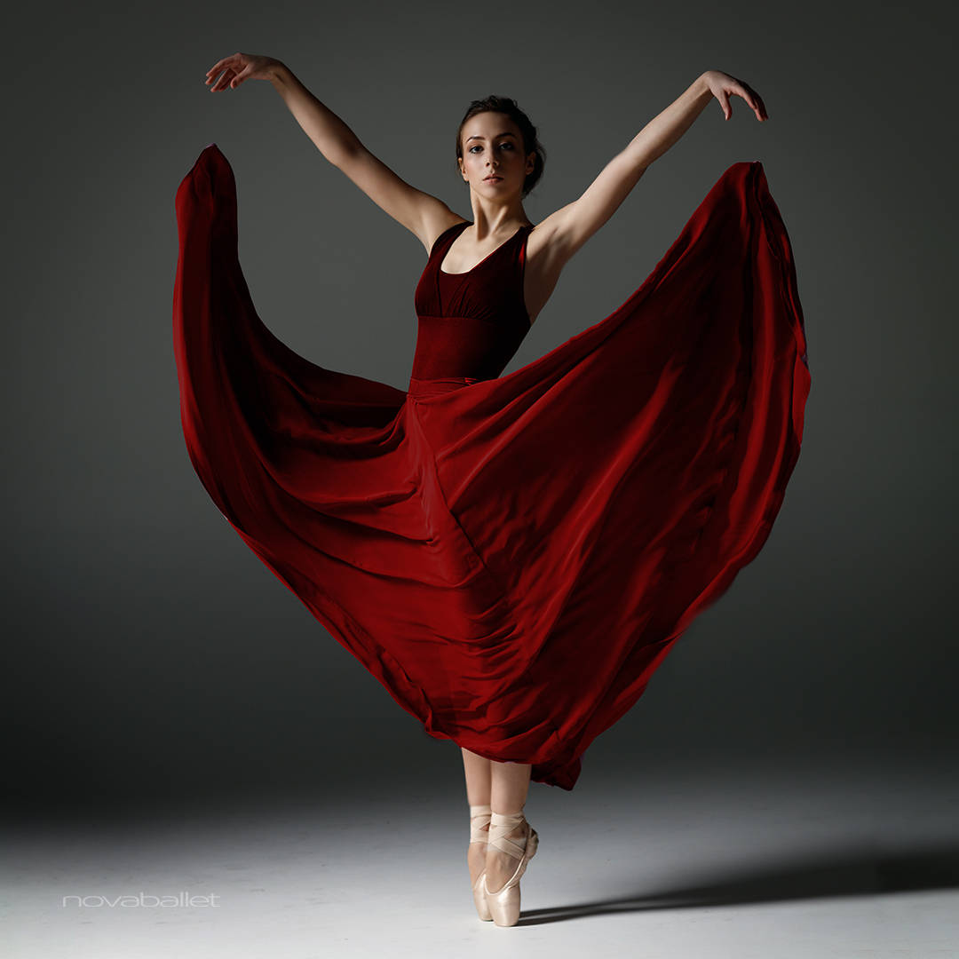 Dans Pose Ballerina i Rød Kjole på Sort Baggrund Wallpaper