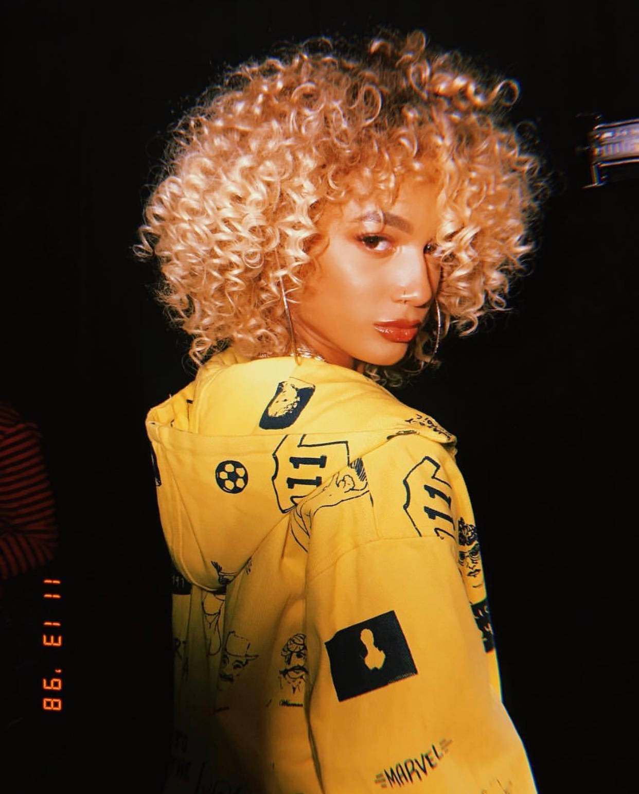 A Woman In A Yellow Jacket With Curly Hair Wallpaper