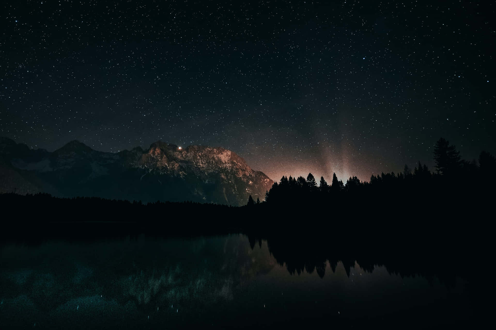 a mountain range with stars and trees in the night