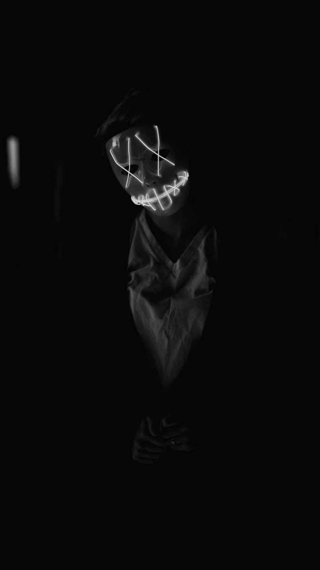 En person i et mørkt rum med et lys på ansigtet. Wallpaper