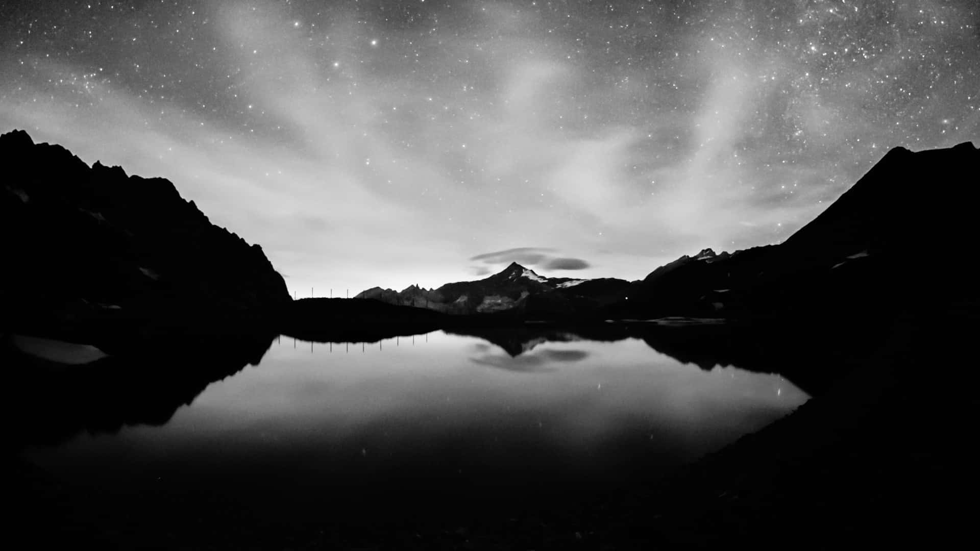 A Black And White Photo Of A Mountain Lake With Stars Wallpaper