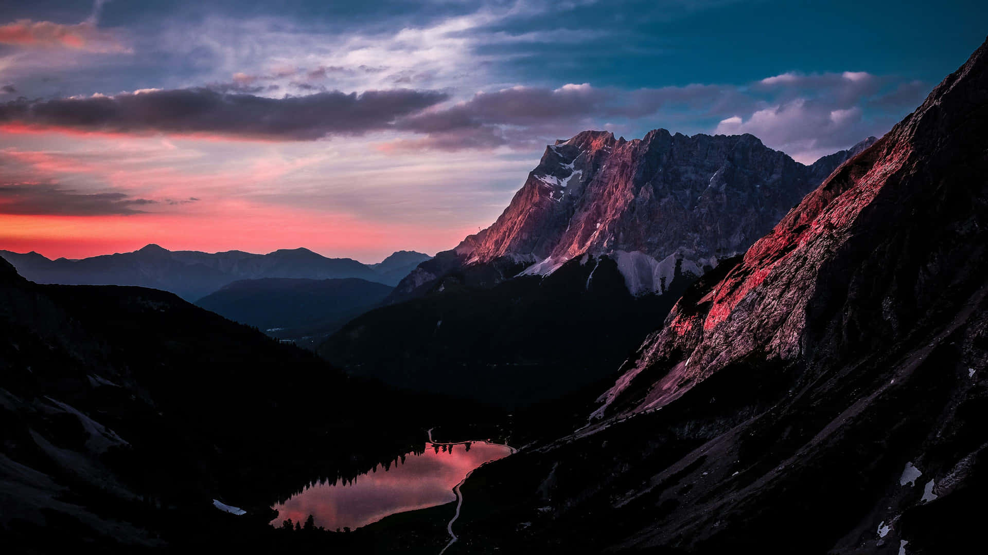 En bjergkæde med en sø og solnedgangs himmel. Wallpaper