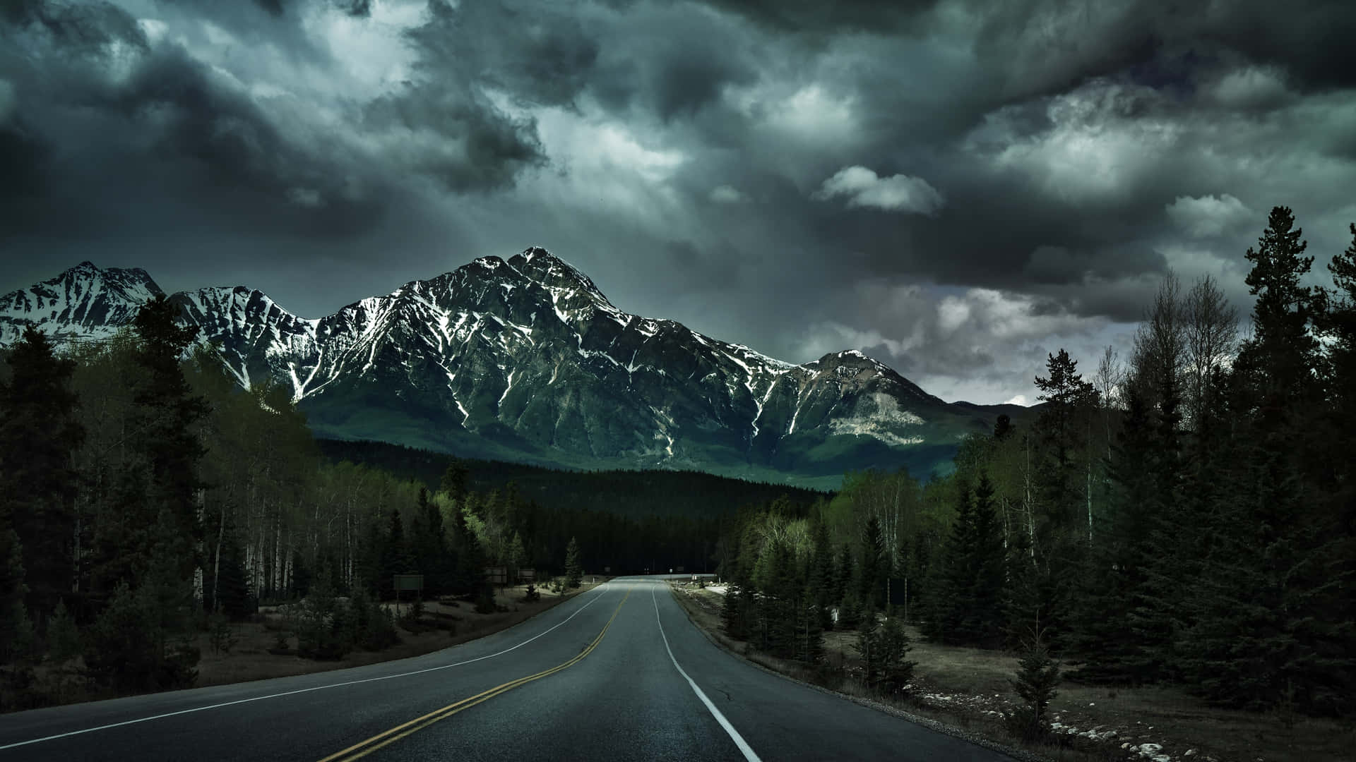 A Road With Mountains And Clouds In The Background Wallpaper