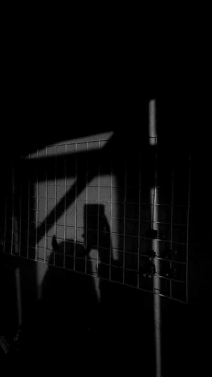 Dark_ Shadowy_ Figure_ Behind_ Grid Wallpaper