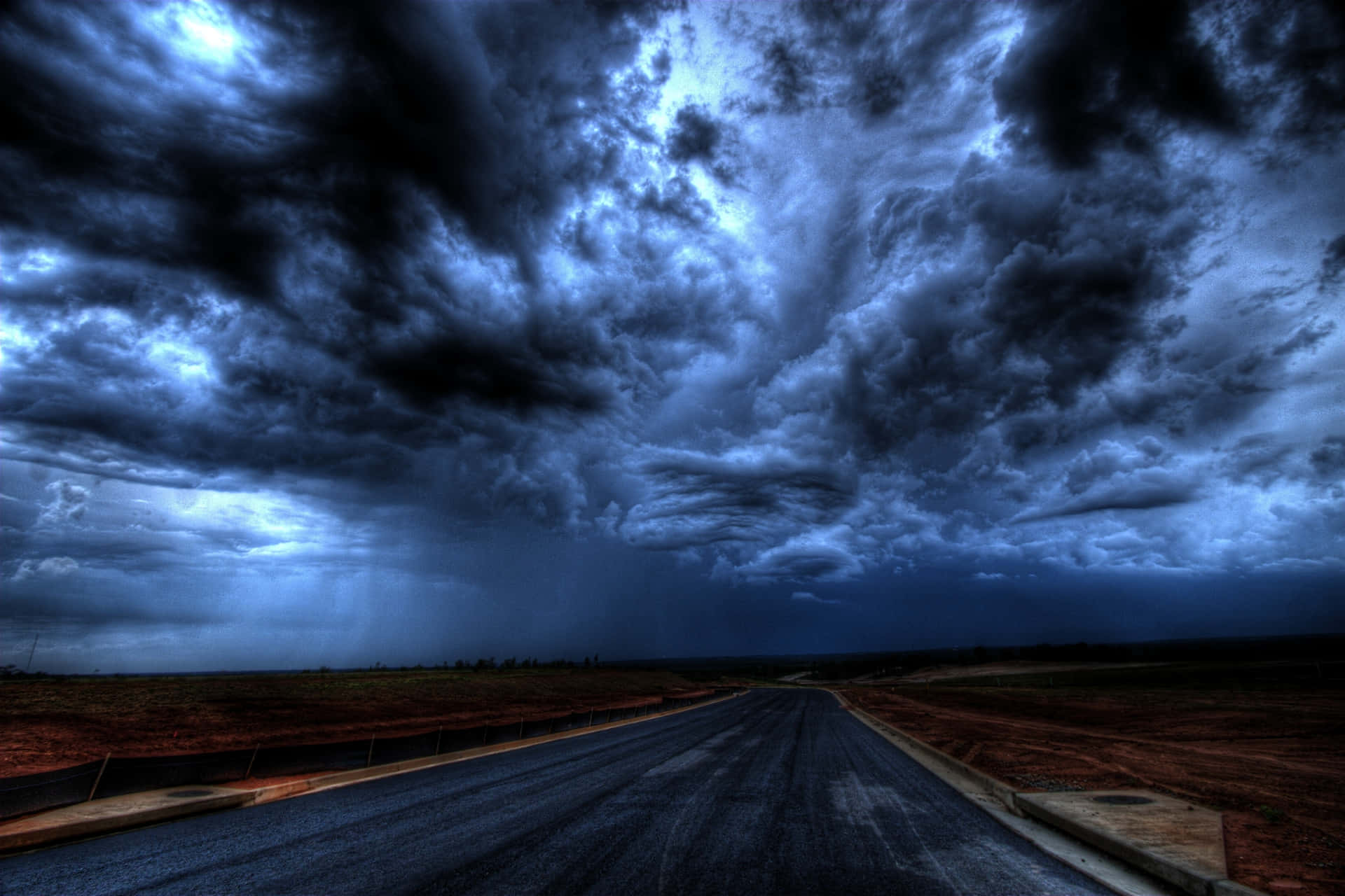 a dark sky with storm clouds over a road