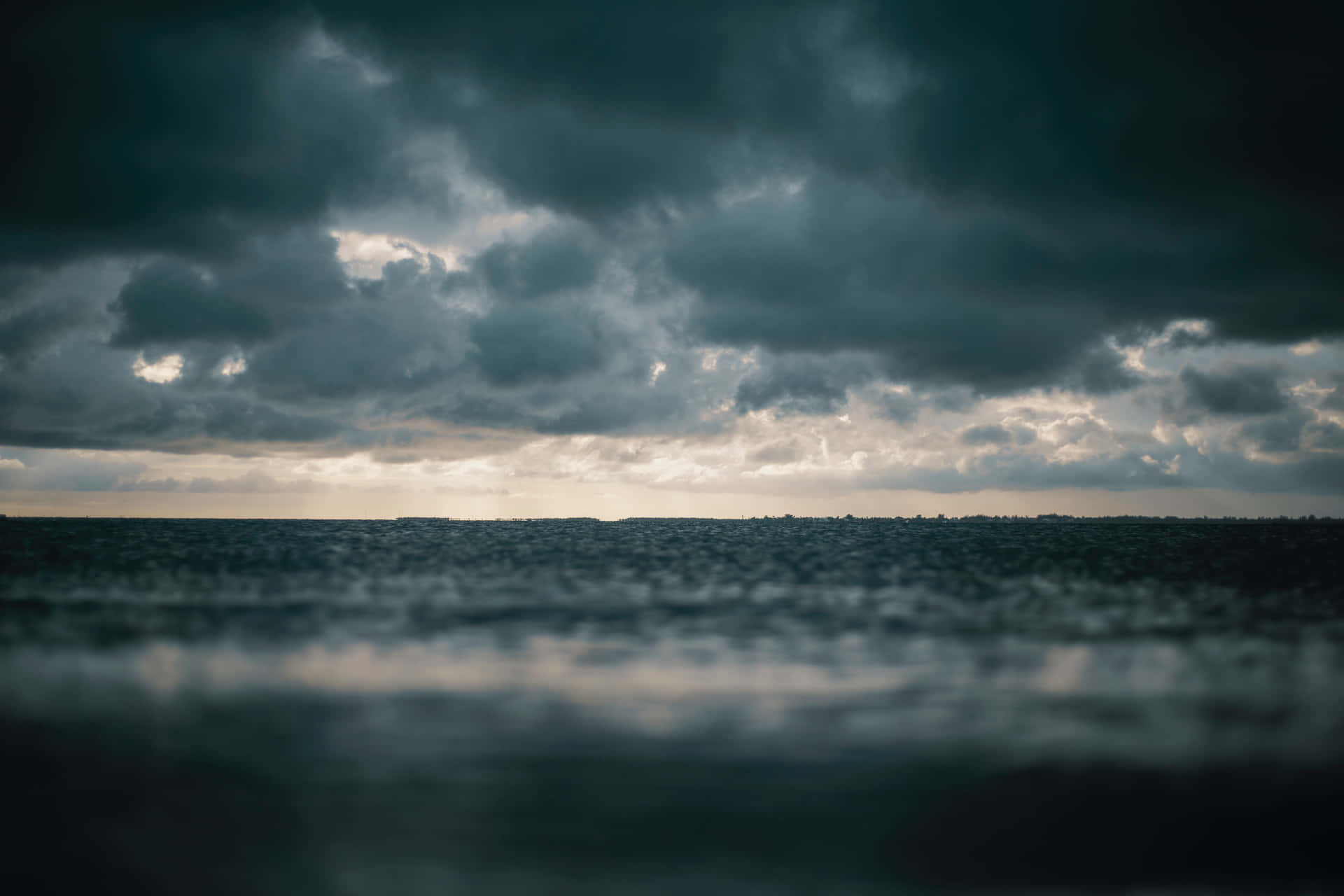 a dark sky over the ocean with a boat in the background