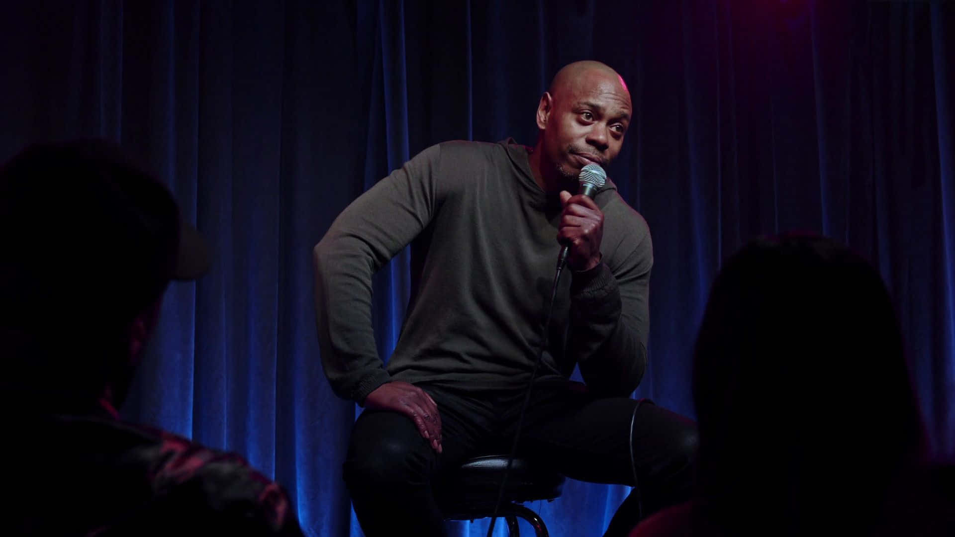 Dave Chappelle On Stage Delivering A Powerful Performance Wallpaper