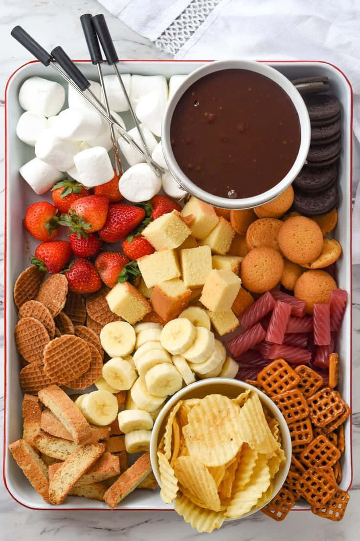a tray with fruit, crackers, and dip