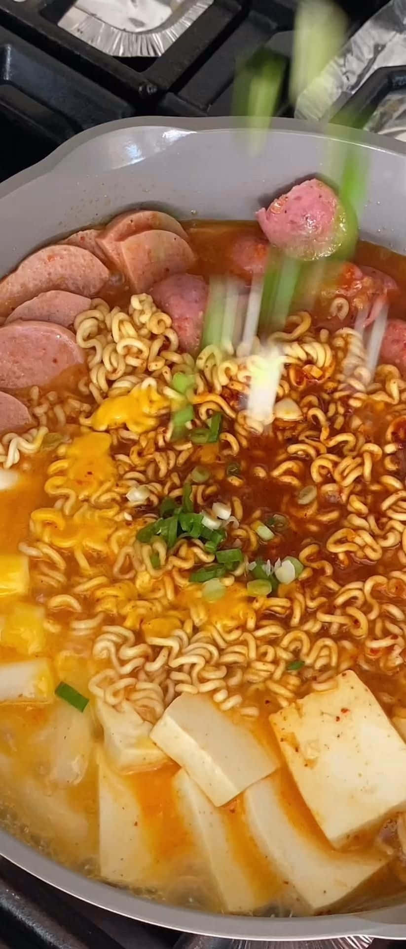 A Pan Of Noodles With Meat And Sausage On Top