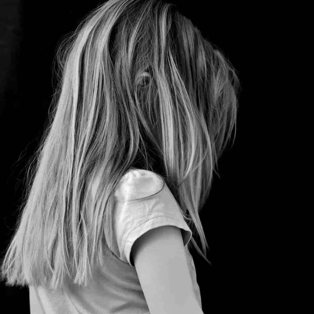 A Girl With Long Hair Is Standing Behind A Black Background
