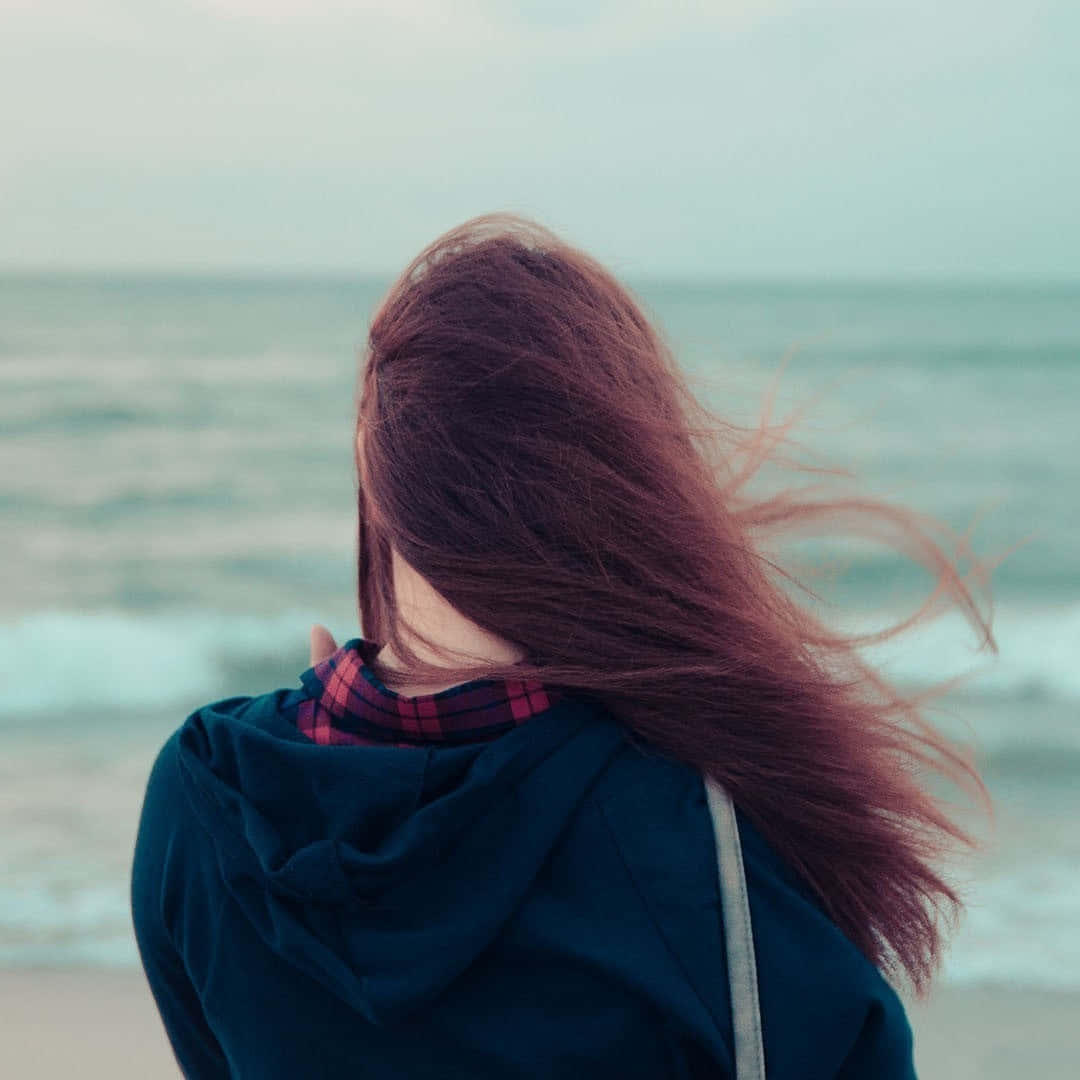 A Woman With Long Hair Standing On The Beach
