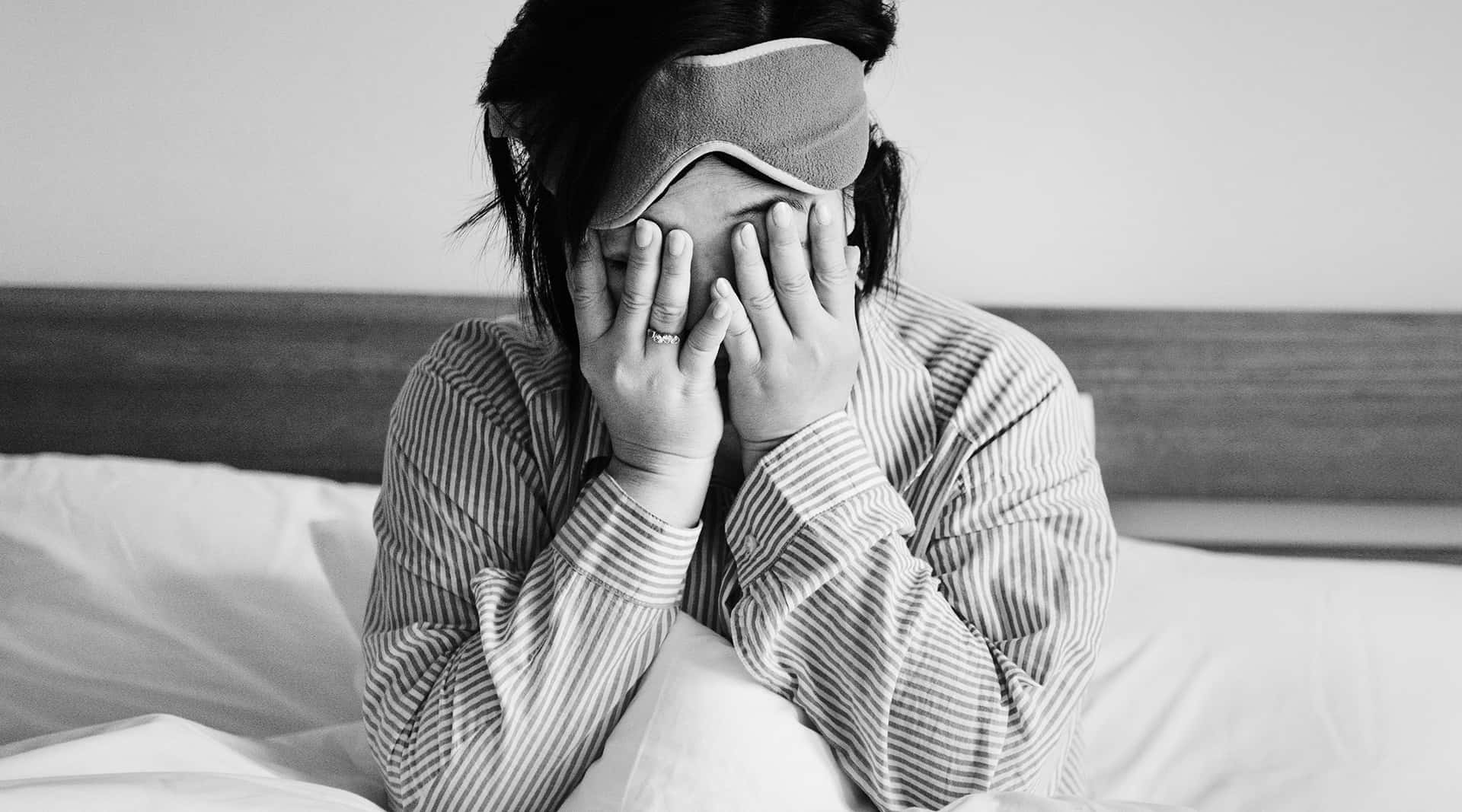 A Woman Is Covering Her Face With A Mask In Bed
