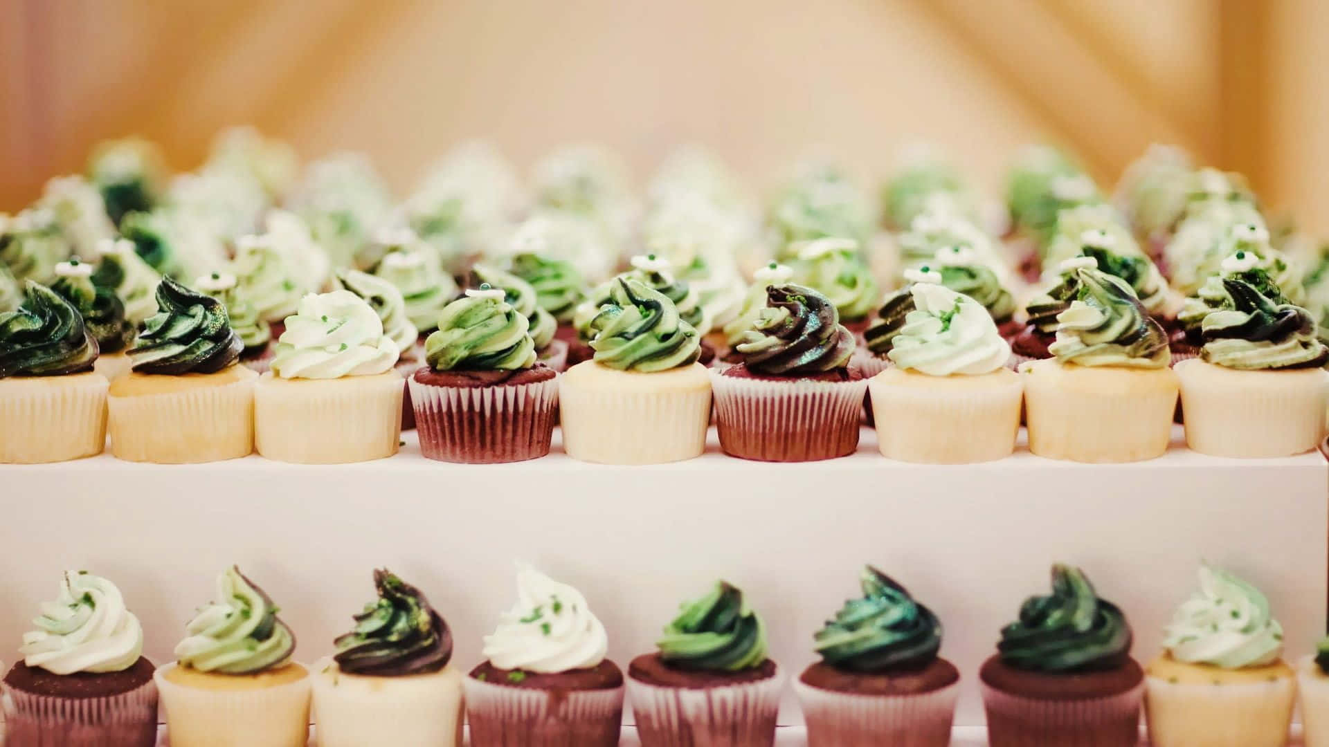 Cupcakes With Green And White Frosting On A White Stand